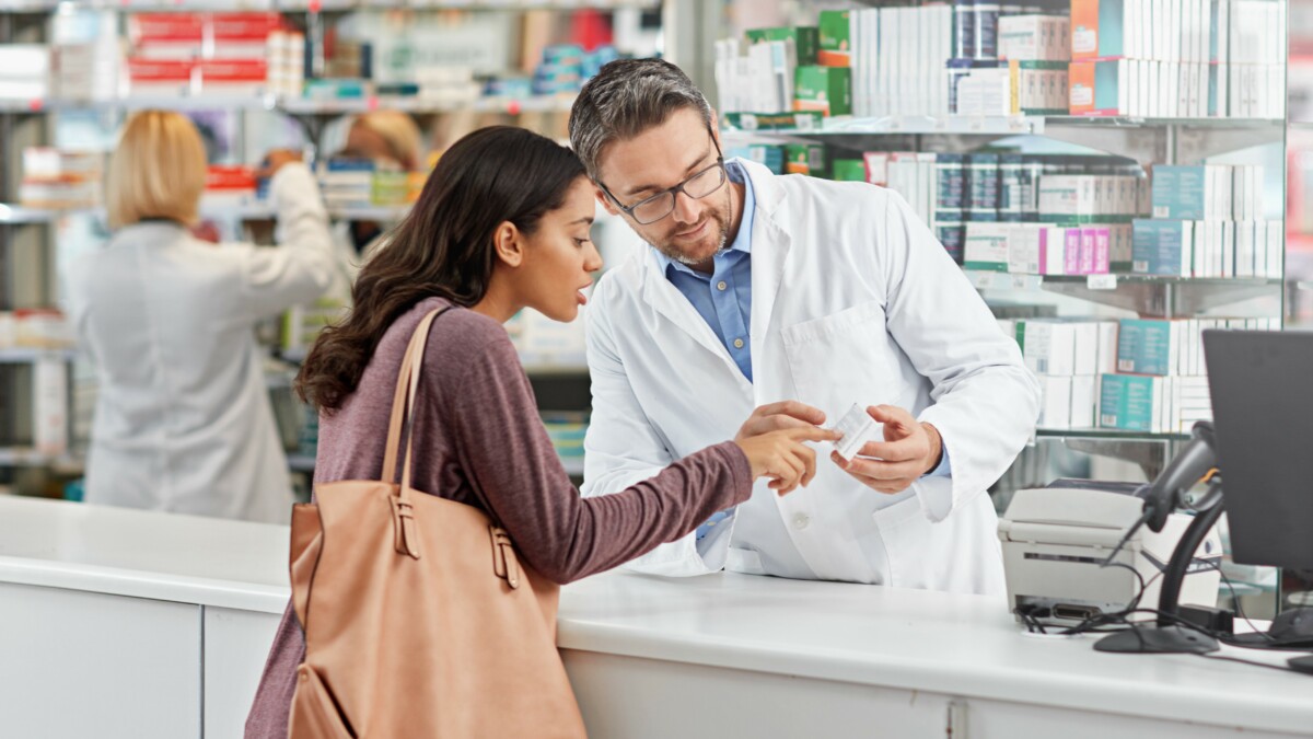 Shot of a male pharmacist assisting a customer at the prescription counter. All products have been altered to be void of copyright infringements
